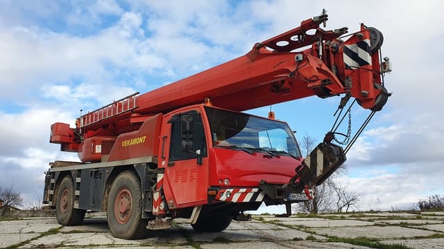 Červený autožeriav DEMAG AC30 City s nápisom VEKAMONT